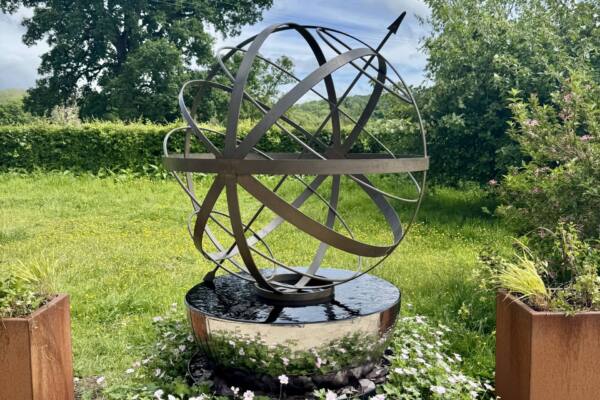 Brass-Armillary-Sphere-paired-with-Cascade-on-a-raised-planter-with-gerainiums-scaled-600x400 Cascade